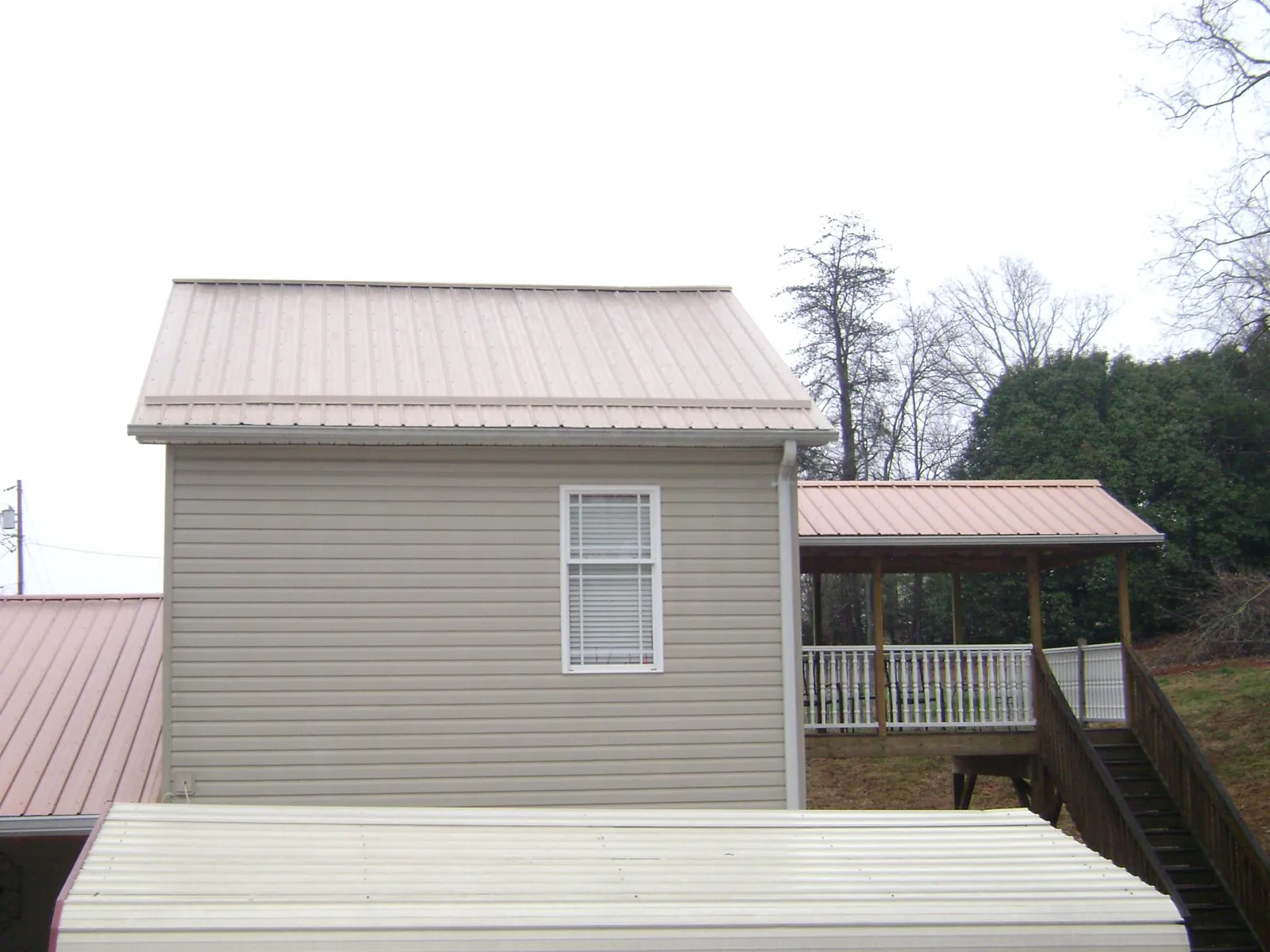 Tan metal roofs on a two story addition and attached porch, from a Roof Replacement job in Herndon
